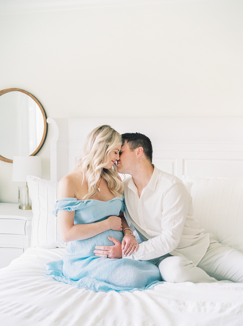 Pregnant couple kissing and holding baby bump